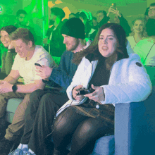 a woman is playing a video game while sitting in a crowd