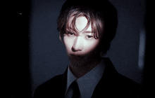 a man in a suit and tie looks at the camera in the dark