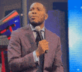 a man in a suit and tie holds a microphone in his hand