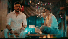 a man and a woman are sitting at a table drinking from cups .