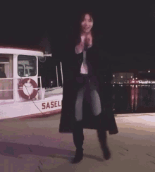 a woman stands in front of a boat that says saselbek on the side