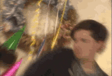 a blurry picture of a man and a cat wearing party hats and ribbons .