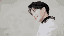a young man wearing a black turtleneck and earrings smiles
