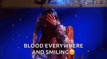 a woman is covered in blood and smiling while standing in a pool of blood .