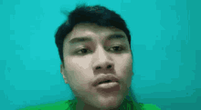a young man in a green shirt is making a surprised face .