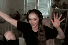 a woman wearing headphones is sitting in front of a microphone with her arms outstretched