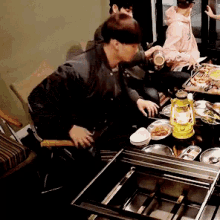 a group of people are sitting around a table with plates of food and a lantern on it