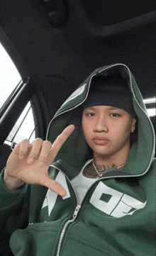 a man wearing a green hoodie with the letter o on it