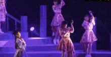 a group of girls are dancing on a stage in purple dresses .