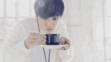 a young man is drinking a cup of coffee .