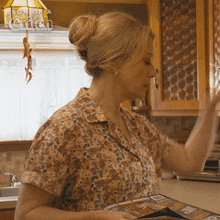 a woman in a kitchen with a son of a bitch logo on the ceiling