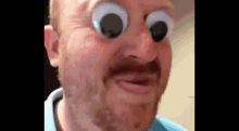 a man with a beard is making a funny face with googly eyes on his face .