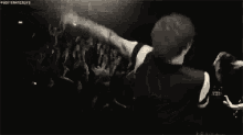 a man is singing into a microphone in front of a crowd of people .