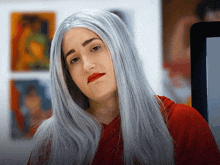 a woman wearing a gray wig and red lipstick looks at the camera