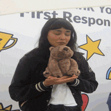 a woman holding a teddy bear in front of a sign that says " first response "