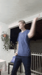 a man in a blue shirt is dancing in front of a chair