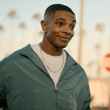 a man wearing a green jacket and a white t-shirt is standing in front of a sign that says netflix