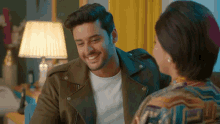 a man in a brown jacket is smiling at a woman