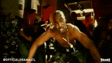 a shirtless man is dancing in front of a crowd of people in a room .