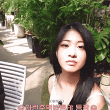 a woman in a white tank top stands in front of a row of potted plants with chinese writing on it