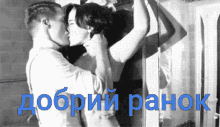 a black and white photo of a man kissing a woman with the words " добрий ранок " in blue letters
