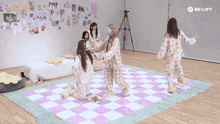 a group of girls in pajamas are dancing on a checkered rug in a room that says belift