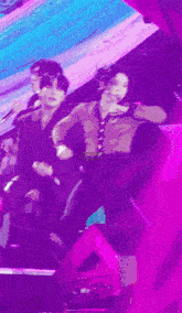 a group of people are dancing on a stage with a purple background