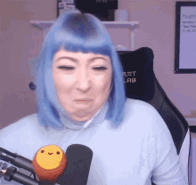 a woman with blue hair is sitting in front of a microphone and a chair with the word ret lab on it