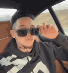 a man wearing sunglasses is sitting in a car with his hand on his face