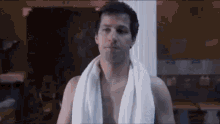 a shirtless man with a towel wrapped around his neck is standing in a bathroom .