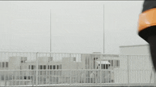 a person wearing black pants and an orange helmet is walking on a balcony