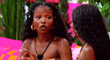 two women are sitting next to each other and one of them is wearing a necklace .