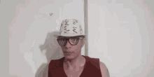 a man wearing a cone hat and glasses is standing in front of a wall .