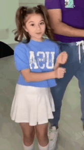 a young girl wearing a blue shirt with the word acu on it