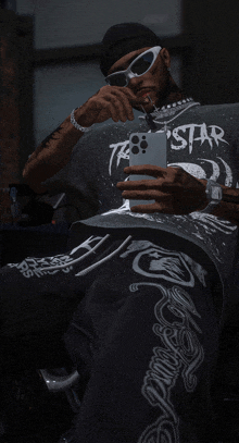 a man wearing sunglasses and a shirt that says star takes a selfie with his phone