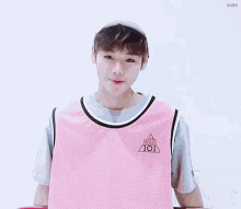 a young man is wearing a pink tank top and holding a skateboard .