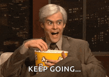 a man in a suit is holding a bucket of popcorn with the words keep going written below him