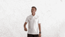 a man wearing a white nike shirt is pointing at his shoulder