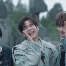 a man in a denim jacket is laughing while standing next to another man .