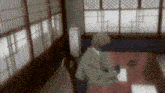 a man in a kimono is sitting at a table in a room with lots of windows .