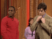 a man in a green suit stands next to another man in a red sweater