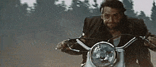 a man in a suit is riding a motorcycle on a dirt road .