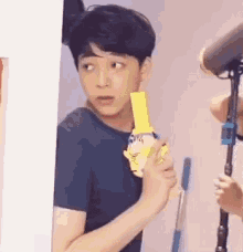 a young man is holding a yellow object in his hand while standing in front of a microphone .