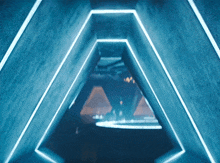 a triangle shaped tunnel with blue lights on the walls and ceiling