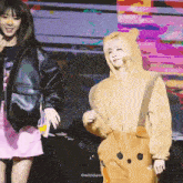 a girl in a bear costume stands next to another girl in a pink skirt