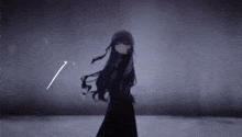 a girl in a black dress is standing in a dark room holding a sword .