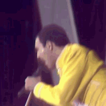 a man in a yellow jacket is singing into a microphone