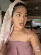 a woman with a towel wrapped around her head is looking at the camera .
