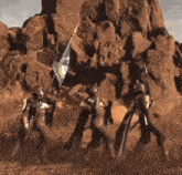 a group of soldiers carrying a flag in front of a large rock formation