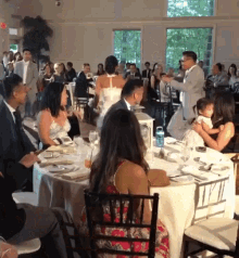 a bride and groom are dancing in front of a crowd of people at a wedding reception